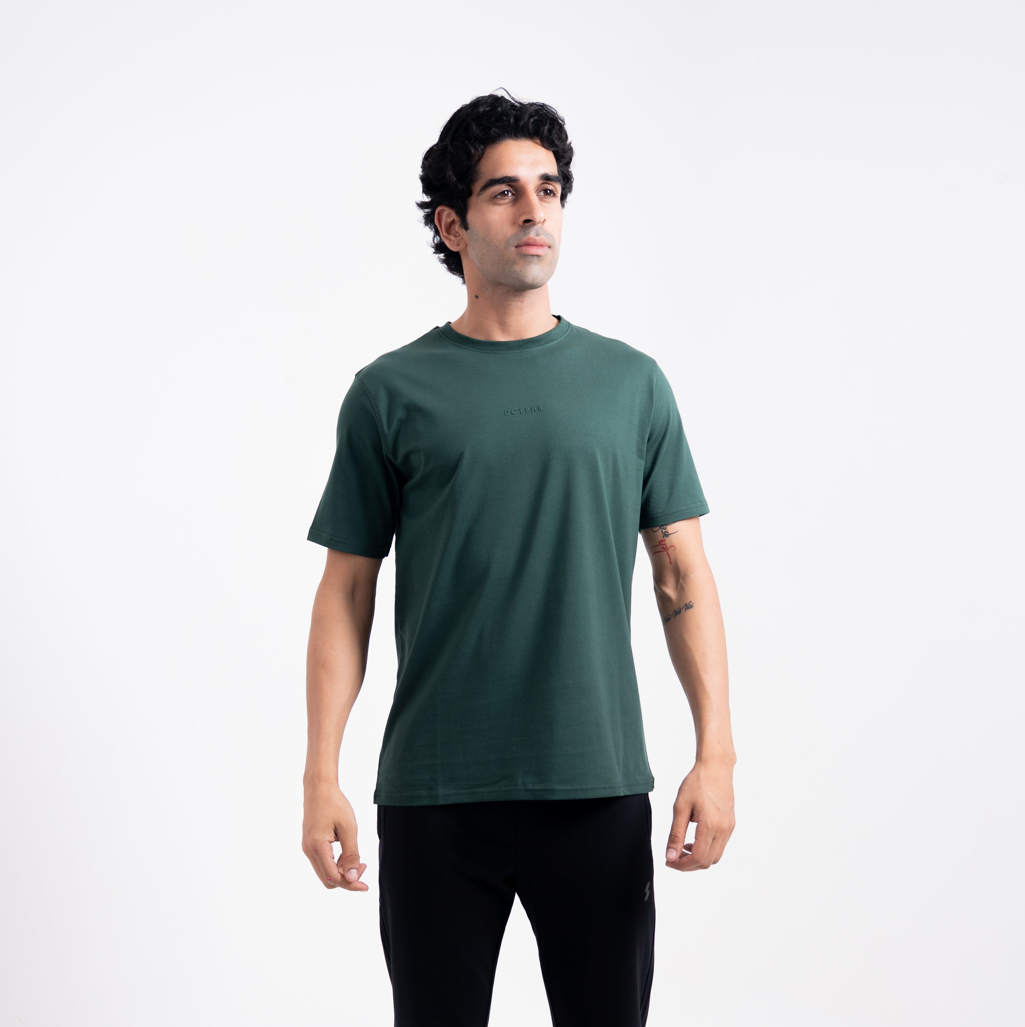 Man wearing a green t-shirt and black pants on a white background
