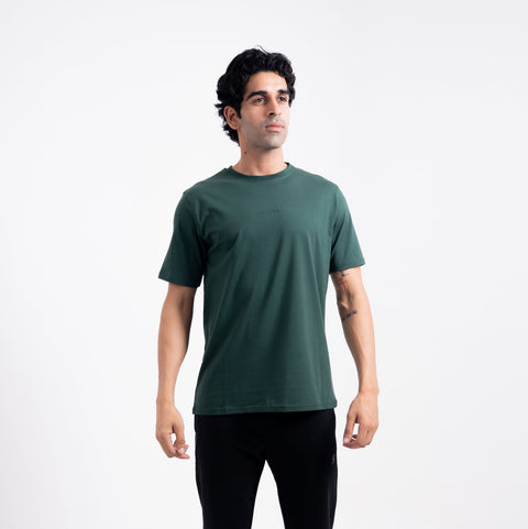 Man wearing a green t-shirt and black pants on a white background