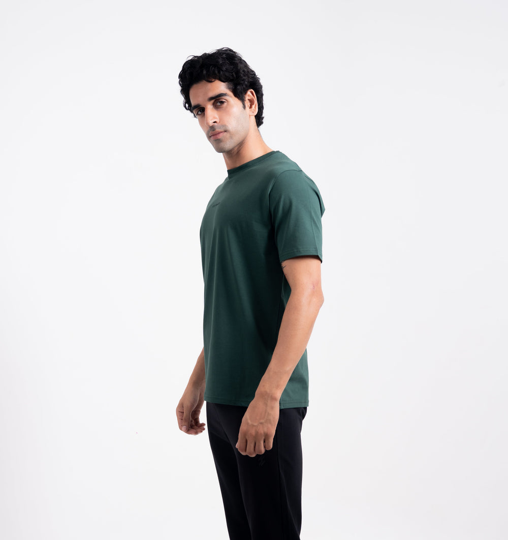 Man wearing a green t-shirt and black pants on a white background