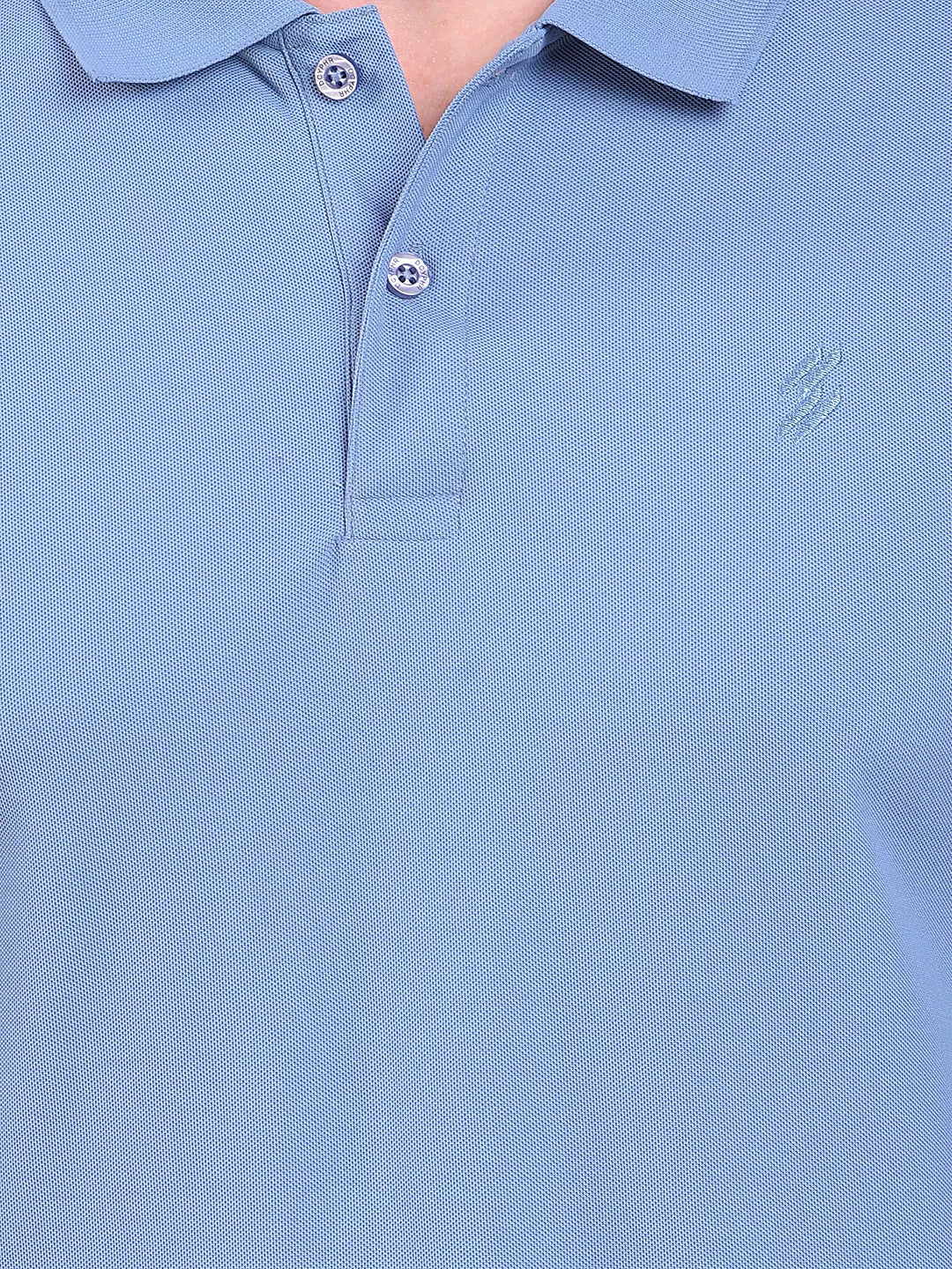 Close-up of a light blue polo t-shirt (DCYPHR Men's Element Polo - Denim Blue) with buttons and a brand logo.