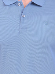 Close-up of a light blue polo t-shirt (DCYPHR Men's Element Polo - Denim Blue) with buttons and a brand logo.