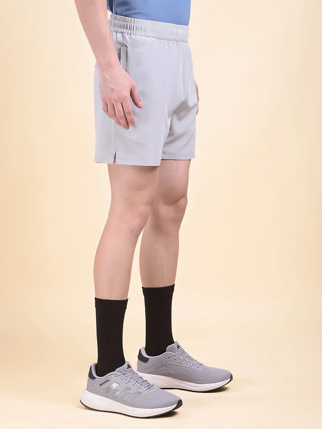 Person wearing light gray shorts (DCYPHR Men's Mono Flex Short-Light Grey) and black socks and sports shoes