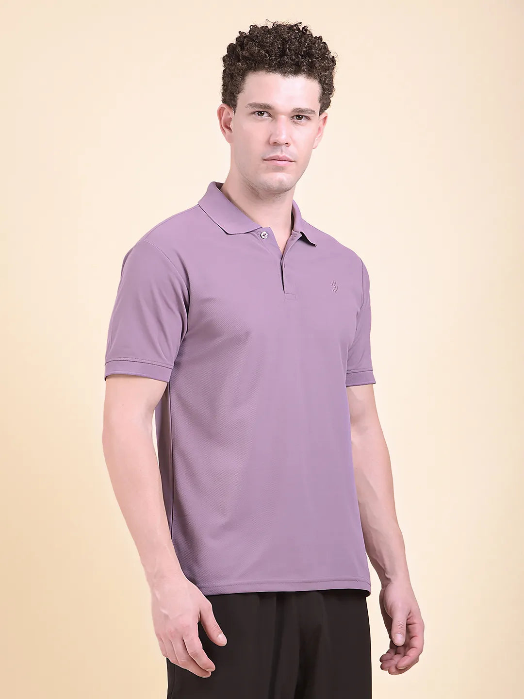 Man wearing a purple polo t-shirt (DCYPHR Men's Element Polo - Dusk Plum) against a beige background facing front camera.