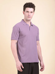 Man wearing a purple polo t-shirt (DCYPHR Men's Element Polo - Dusk Plum) against a beige background facing front camera.