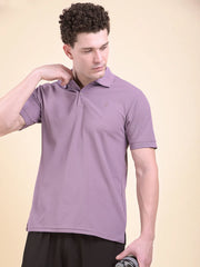 Man wearing a purple polo t-shirt (DCYPHR Men's Element Polo - Dusk Plum) against a beige background, facing downward.